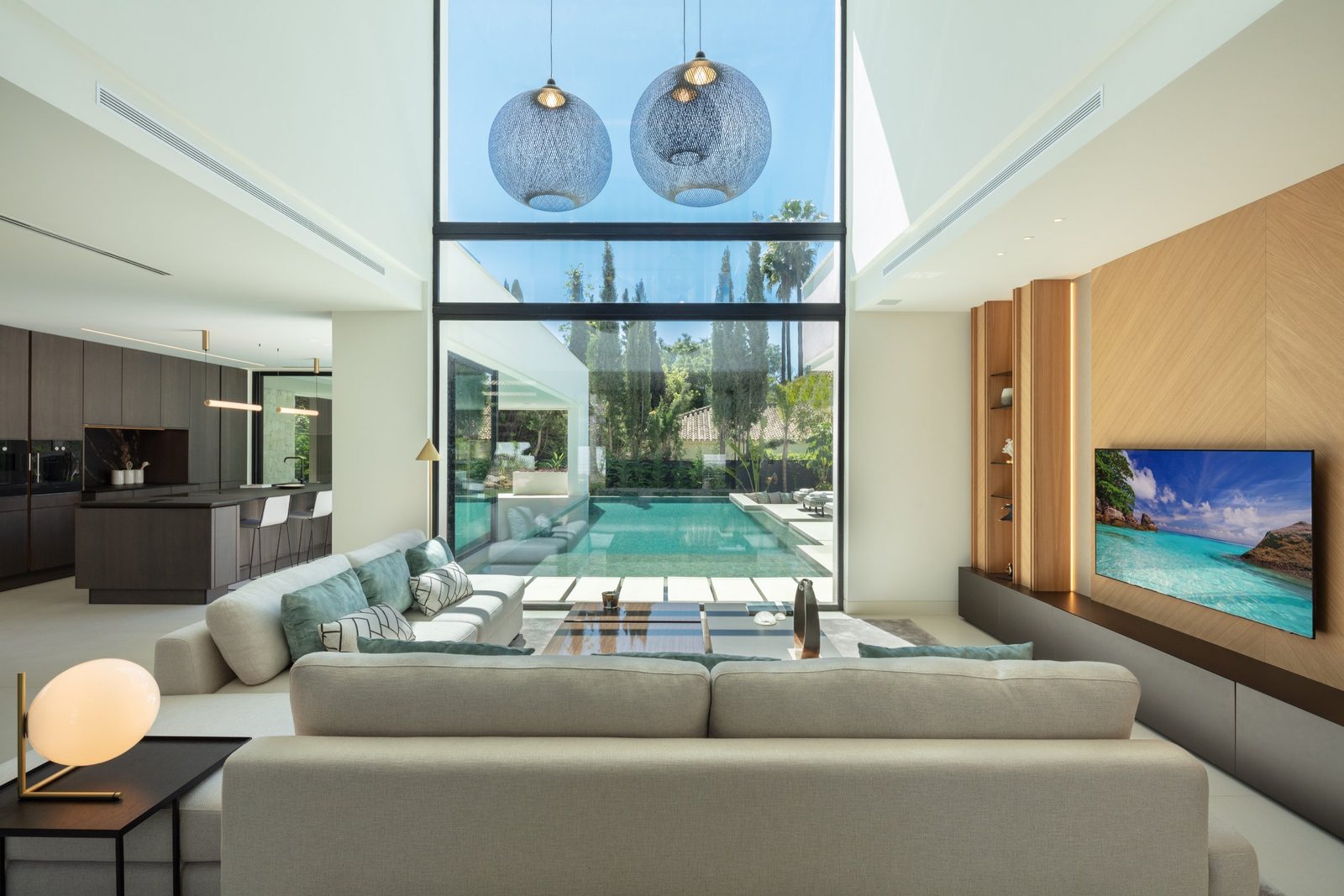 Modern open-plan living room and kitchen overlooking the pool of a 5-bedroom villa in Málaga - The Estates
