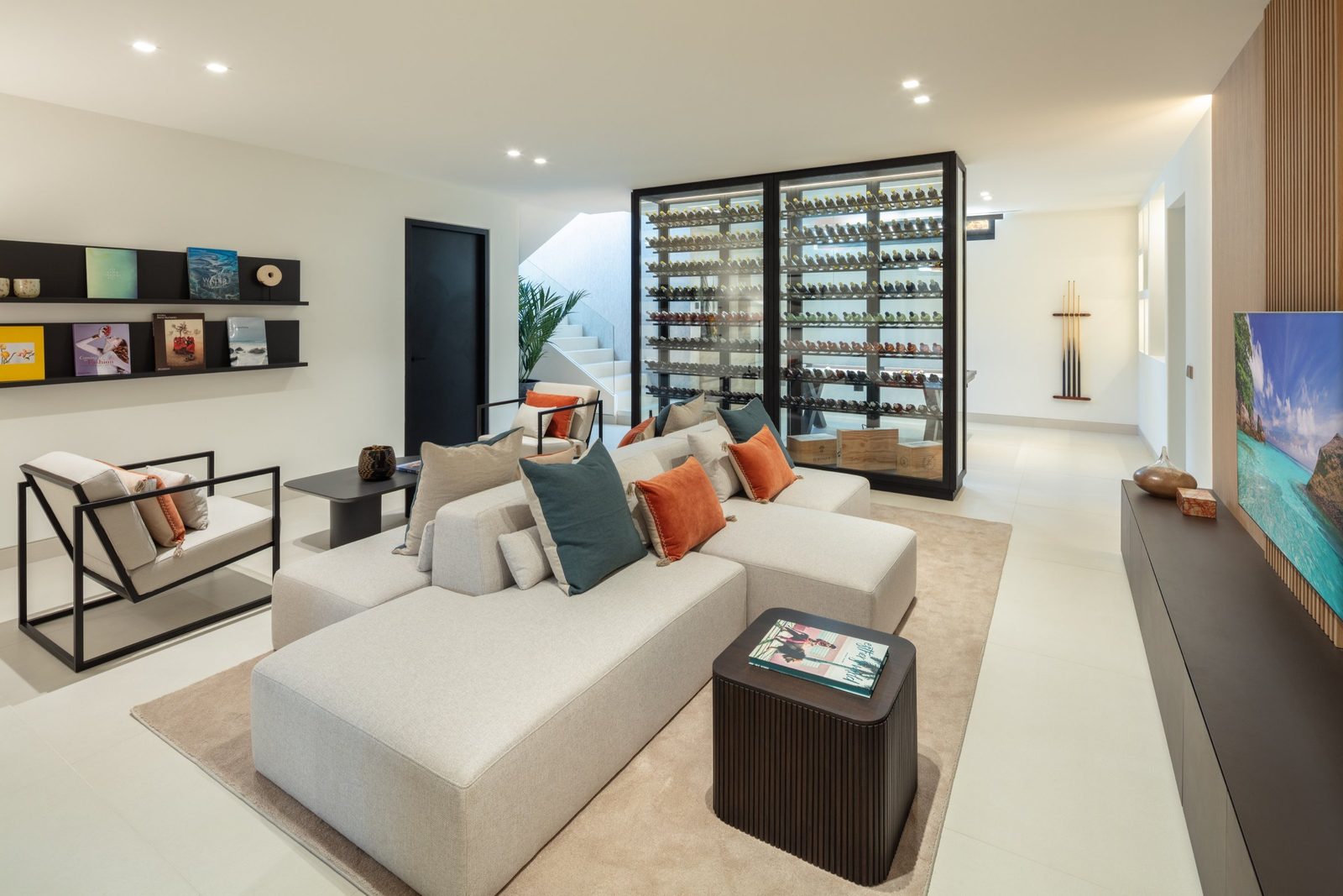 Contemporary lounge with sectional seating, TV and glass-enclosed wine cellar of a 5-bedroom villa in Málaga - The Estates