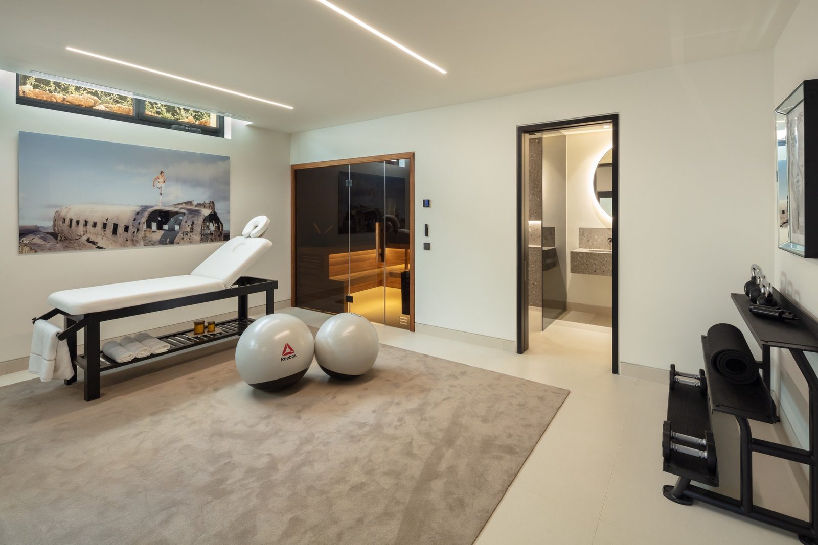 Private gym and wellness room with massage table, exercise equipment and sauna in a 5-bedroom villa in Málaga - The Estates