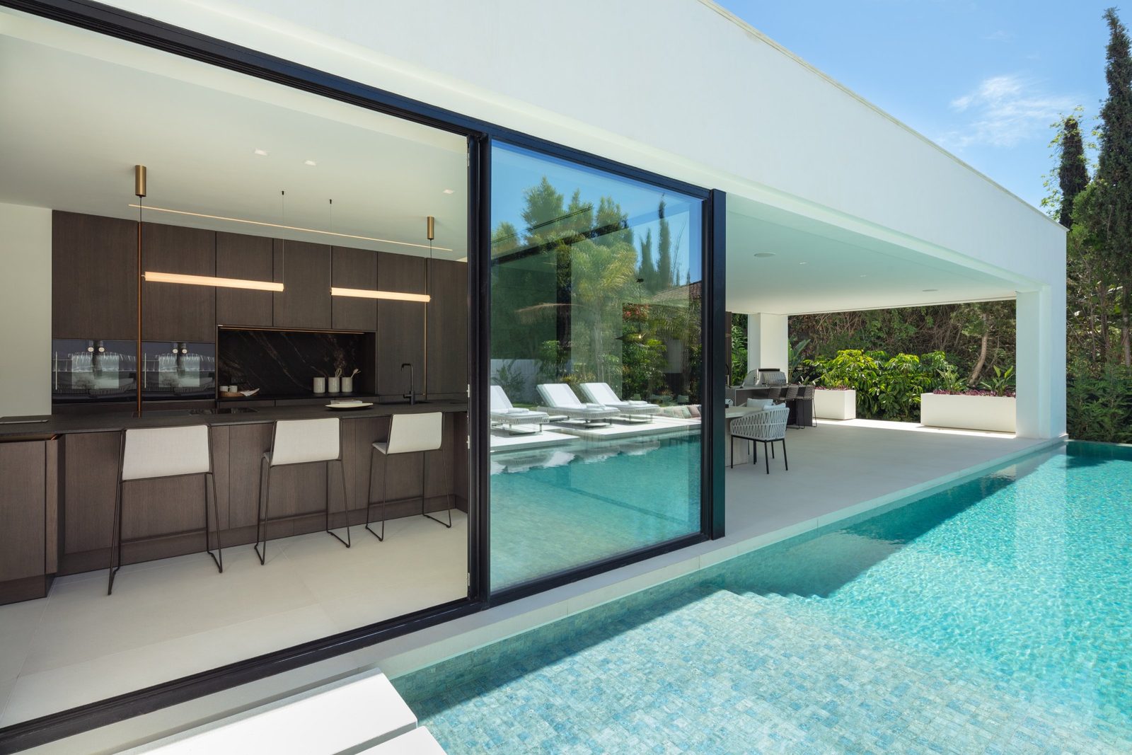 Modern kitchen opening onto a pool terrace at a 5-bedroom villa in Málaga - The Estates
