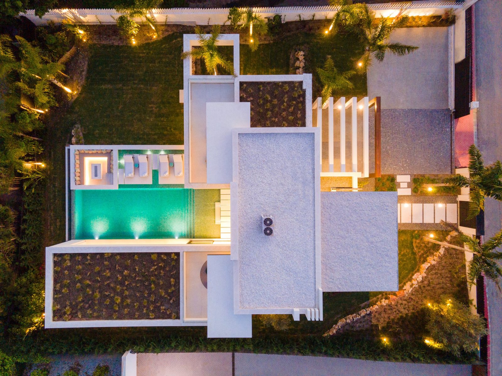 Aerial night view of a modern villa with illuminated pool and landscaped gardens in Marbella, Málaga - The Estates
