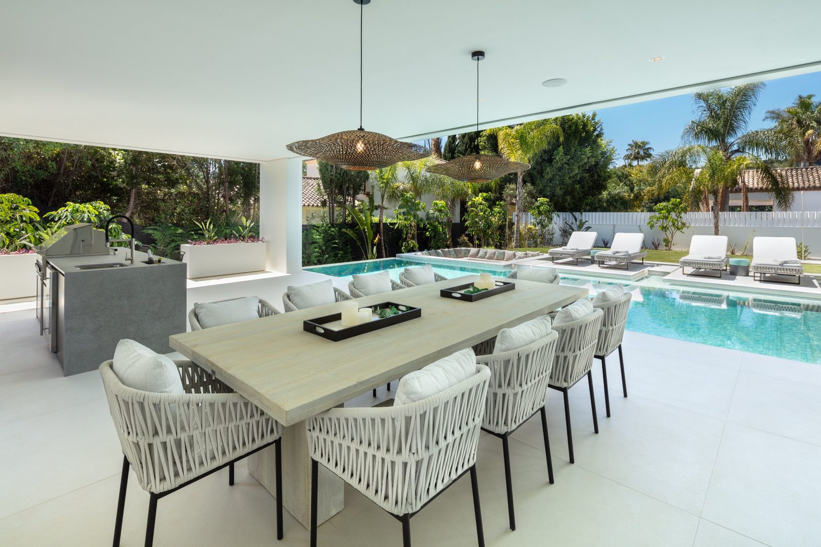 Covered outdoor dining area with summer kitchen, swimming pool and loungers at a 5-bedroom villa in Málaga - The Estates