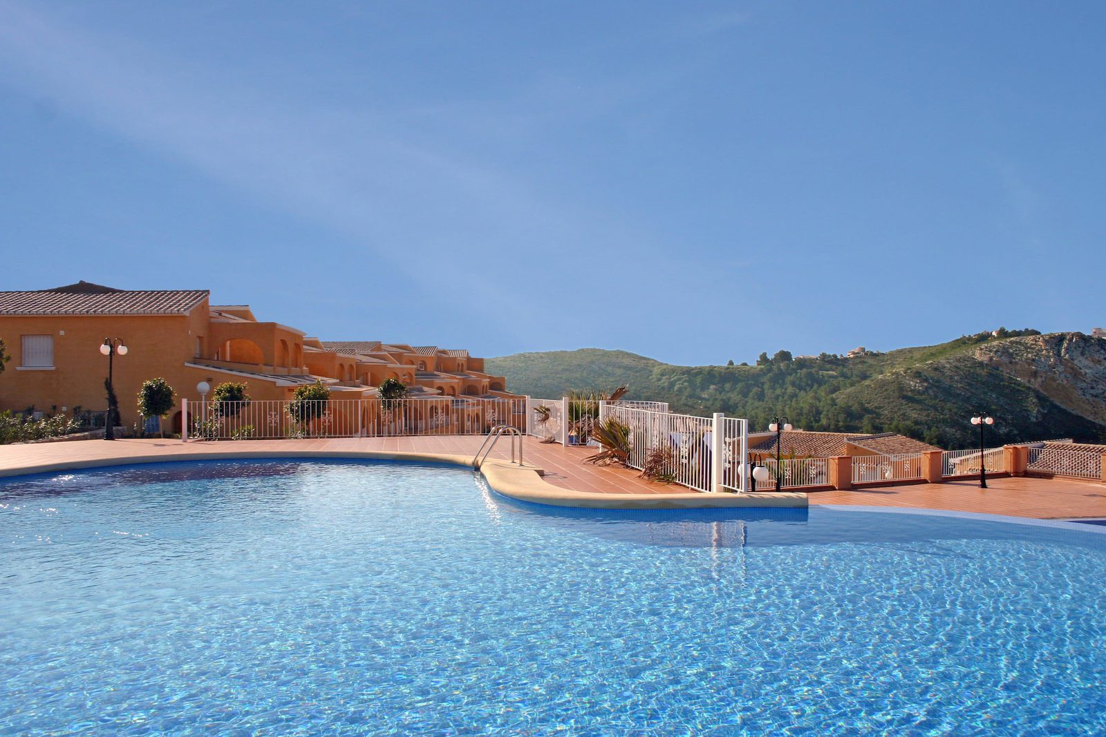 A sunny pool area with a view of a 3-bedroom apartment in Benitachell - The Estates