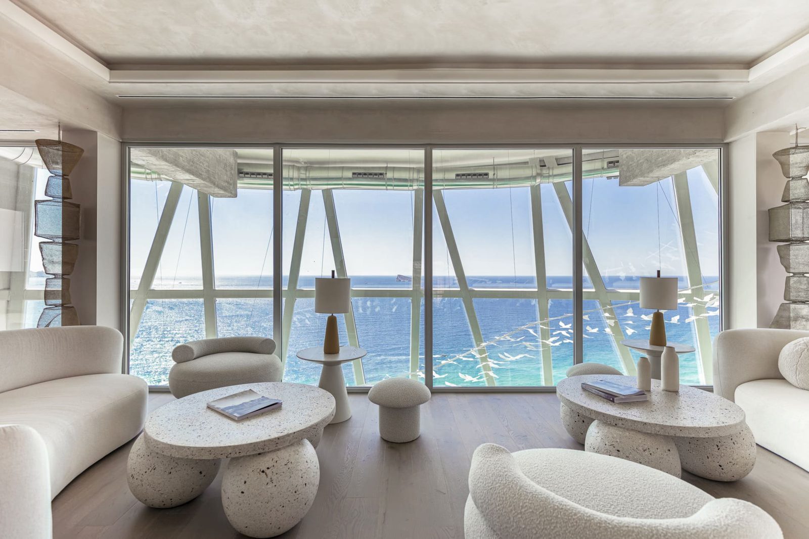 Modern living room with curved sofas, terrazzo coffee tables and panoramic sea views in a 2-bedroom apartment in Benidorm - The Estates