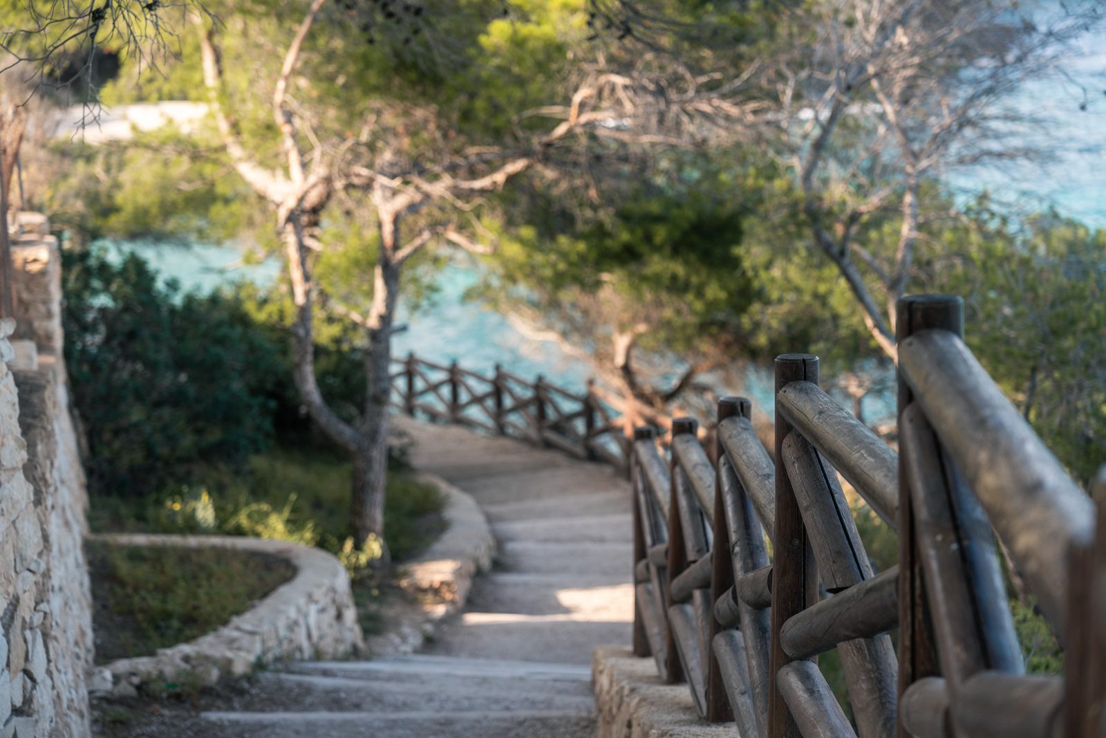 A wooded stairway with wooden railings overlooking turquoise sea in Benissa - The Estates